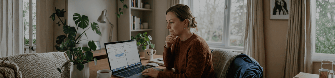A virtual assistant at a laptop pausing before pasting a client email into an AI chat window, soft natural light.